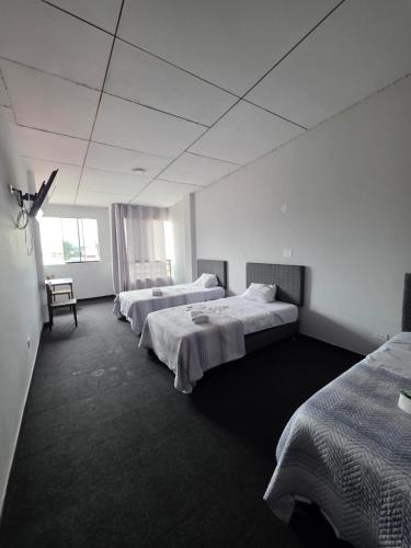 a room with three beds and a chair in it at Javaz Hospedaje in Tarapoto