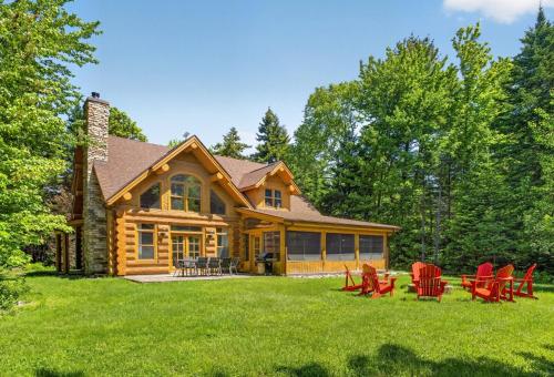 a log home with red chairs in the yard at Fiddler Lake Resort - Bear 25 in Mille-Isles