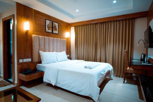 a hotel room with a large bed and a television at Sri Vishnu Grand in Vellore