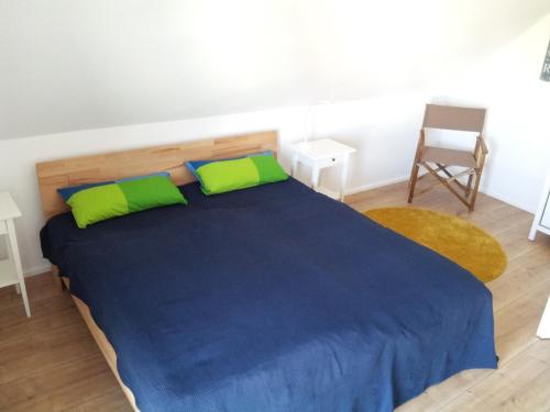 a bedroom with a blue bed with green pillows and a chair at Das Rügenhaus in Lancken-Granitz