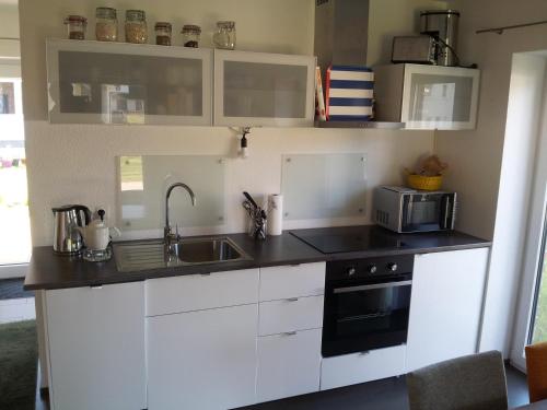 eine Küche mit weißen Schränken, einer Spüle und einer Mikrowelle in der Unterkunft Das Rügenhaus in Lancken-Granitz