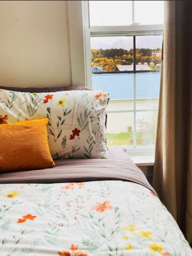 a bed with a floral bedspread and a window at Fin's Studio, Fundy Park in Alma