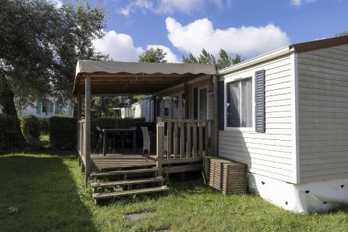 a white mobile home with a porch and an awning at Camping Les Nysades in Mirepoix