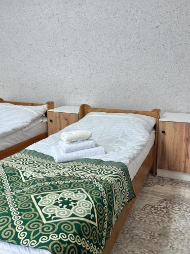 two beds with towels on top of them in a room at Ilgiz Guest House in Bokonbayevo