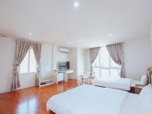 a bedroom with two beds and a desk and two windows at Khách sạn Phúc Thành in Hanoi