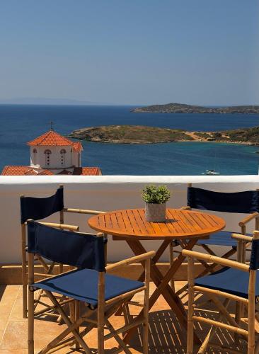 a wooden table and chairs on a balcony with the ocean at Andros Villa in Andros