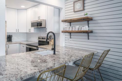 a kitchen with a marble counter top and chairs at Modern-Rustic Beach Renovation Direct Oceanfront Penthouse in Kahana