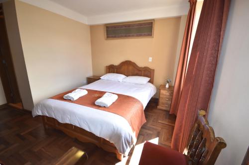 a bedroom with a bed with two towels on it at Fuente de Agua in Cusco