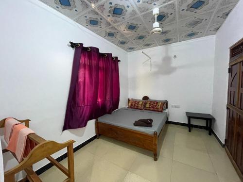 a room with a bed and a purple curtain at ocean breeze in Challi