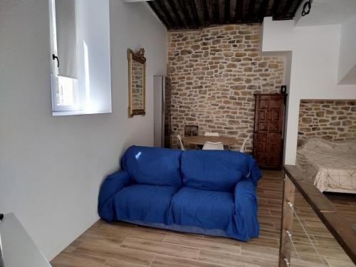 a blue couch in a room with a brick wall at Trévoux centre appartement climatisé in Trévoux