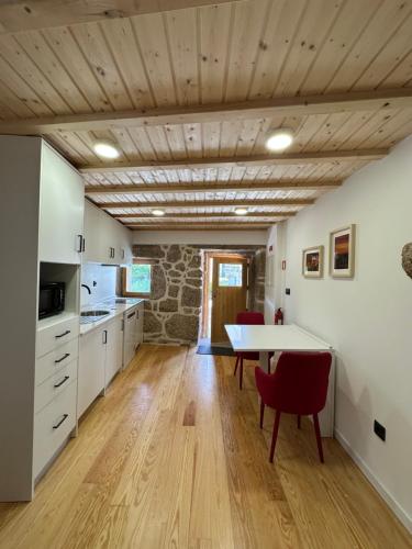 a kitchen with white cabinets and a table with red chairs at Casa N'Aninhas - Santar in Santar