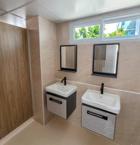 a bathroom with two sinks and two mirrors at Hotel Backpack BTS ปุณณวิถี in Bangkok