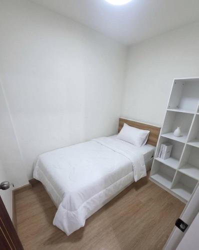 a bedroom with a white bed and a book shelf at Hotel Backpack BTS ปุณณวิถี in Bangkok