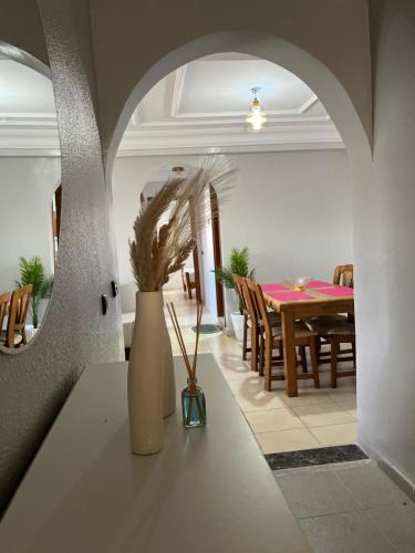 a dining room with a table and a vase with a plant at charmant appartement forêt et mer in Tangier