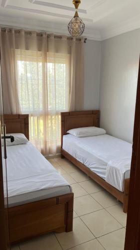 two beds sitting in a room with a window at charmant appartement forêt et mer in Tangier