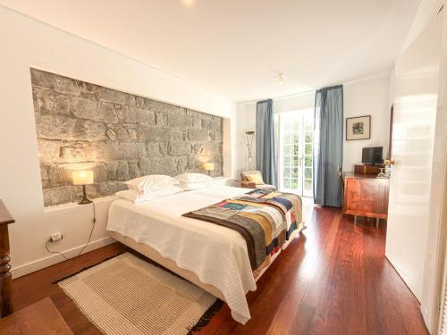 a bedroom with a large bed and a stone wall at Quinta das Buganvílias in Castelo Branco