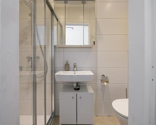 a white bathroom with a sink and a shower at Alpenplatzl XS in Bad Hofgastein
