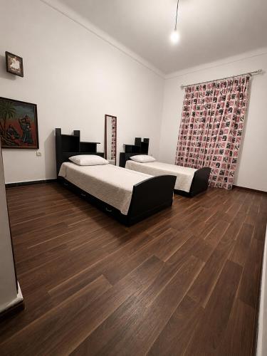 a bedroom with two beds and a wooden floor at Le coin vert in Rabat