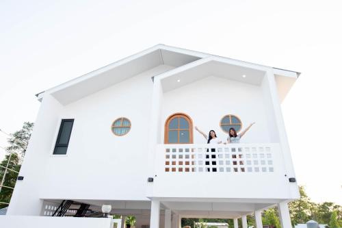 two people standing on the balcony of a white house at Amornrut Hill 03 in Ban Tao Than