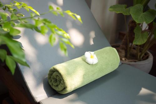a green towel with a white flower sitting on a chair at Hotel Five.S in Kampot