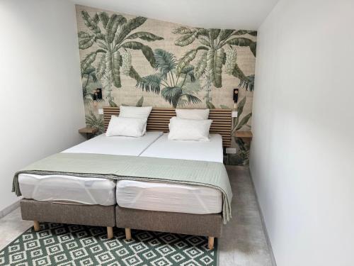 a bedroom with a bed with a mural of palm trees at Les Iles d'ici in Rochefort