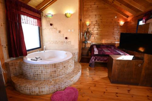 a bathroom with a tub and a television in a room at סוויטות חלב ודבש in Kefar Zetim