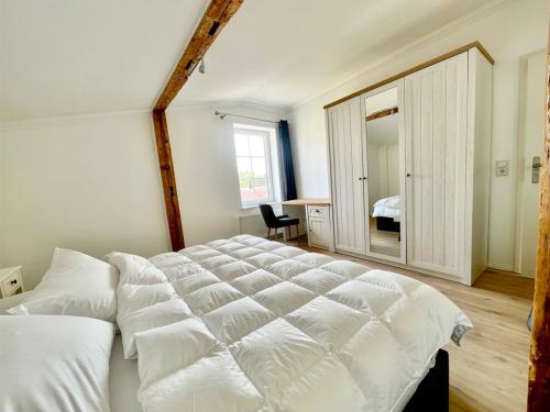 a bedroom with a large white bed and a mirror at Fewo-meerblick-Rügen in Altefähr
