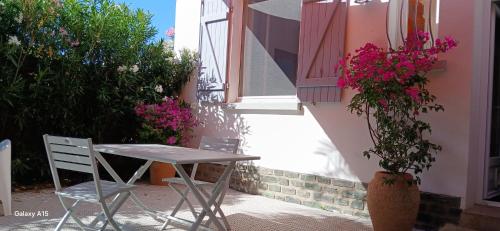 a table and chairs next to a building with flowers at Le chat bleu in Beauvoir-sur-Mer