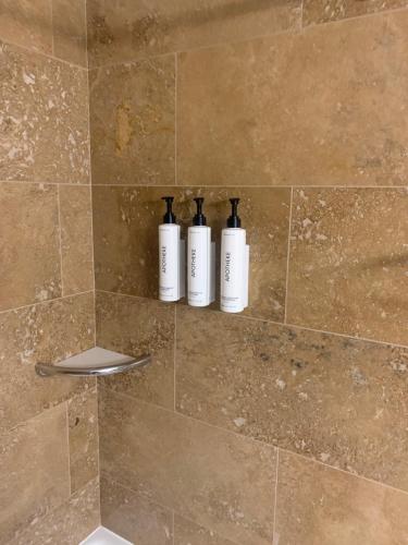 three bottles of soap are sitting on a shelf in a shower at Prestige Inn Nelson in Nelson