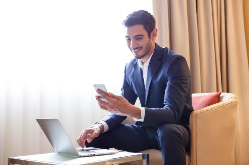 a man in a suit sitting on a chair with a laptop at Novotel Jeddah Tahlia in Jeddah