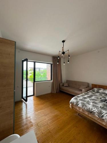 a bedroom with a bed and a couch and a window at Bazaleti Lake Family Apartment in Chanadirtkari