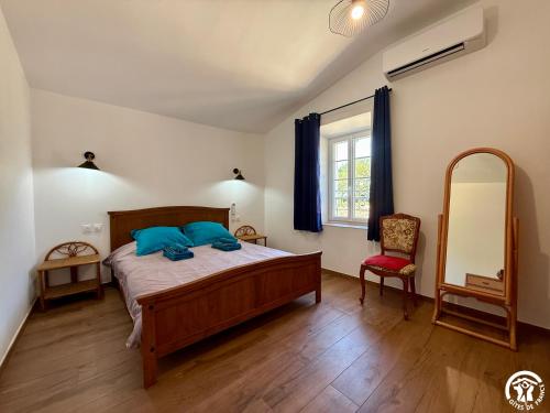 a bedroom with a bed and a mirror and a chair at Château de Prax Viel - piscine et mini ferme, climatisé in Lagrasse