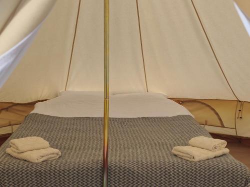 a bed in a tent with two towels on it at ILLU Glamping in Trebujeni