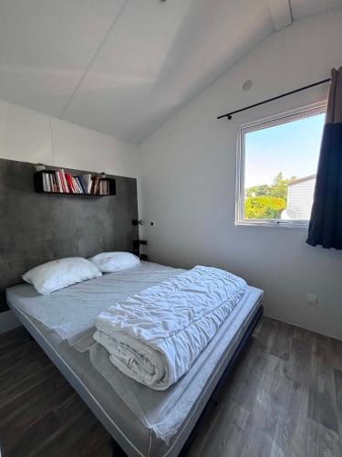 a bedroom with a large bed with a window at Camping Oléron Cap Soleil MH Climatisé in Saint-Denis-dʼOléron