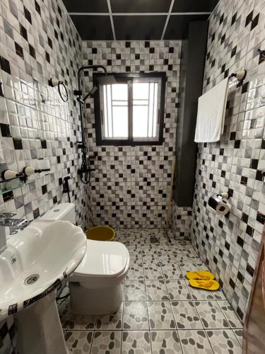 a bathroom with a white toilet and a sink at Western Suites in Douala