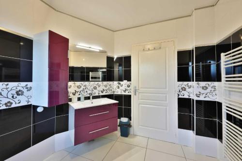 a bathroom with purple cabinets and black and white tiles at Villa Fontenailles in Mâcon