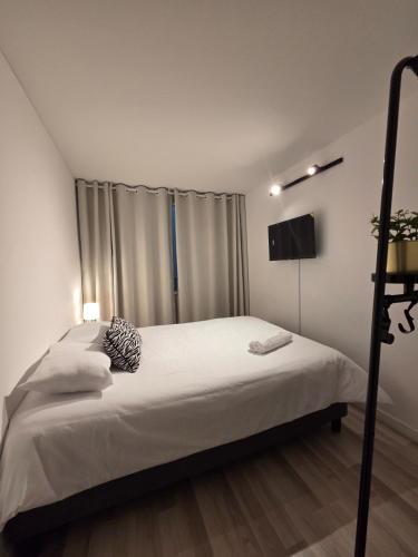 a bedroom with a bed with white sheets and a television at Andes 97 Guest House in Bogotá
