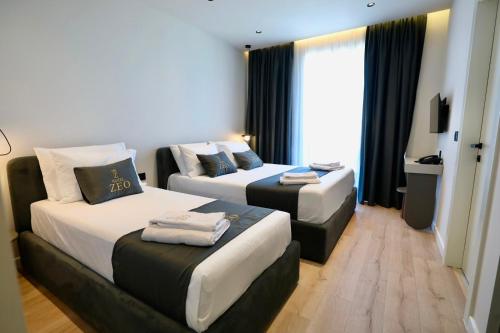 a hotel room with two beds and a couch at Zeo Hotel Saranda in Sarandë