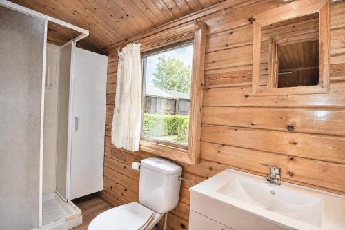 a bathroom with a toilet and a sink and a window at Cabaña Los Leones de Cabárceno in Penagos