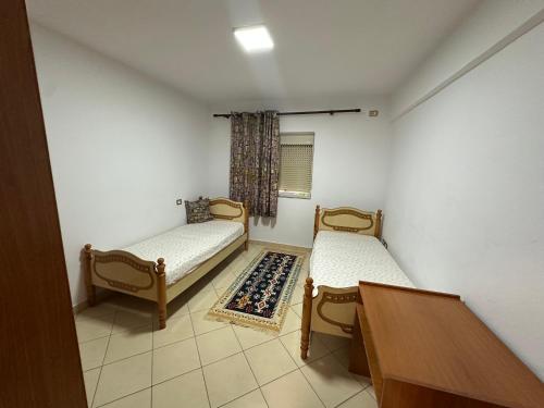 a room with two beds and a table and a window at Bledis Apartments in Lushnjë