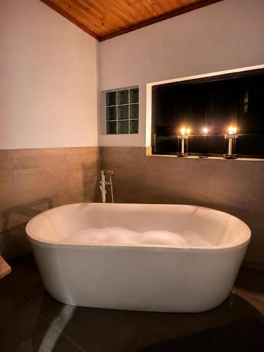 a white bath tub in a bathroom with two candles at FollyFoot Manor in Midrand