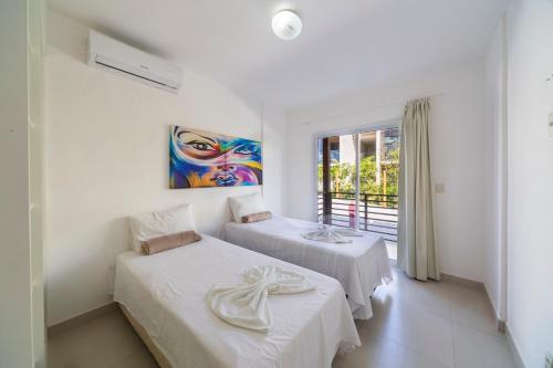 two beds in a white room with a window at Areias de Itacimirim in Itacimirim