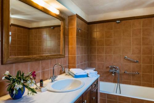 a bathroom with a sink and a tub and a mirror at Kamares Private Pool stone Villa in Makhairoí