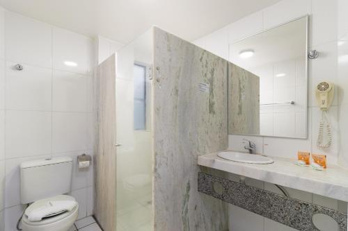 a bathroom with a toilet and a sink and a mirror at Hotel Nacional Inn Recife Aeroporto in Recife