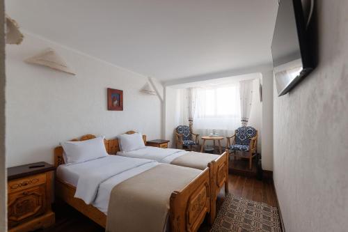 two beds in a room with a table and chairs at Hanul Ancutei in Arămoaia