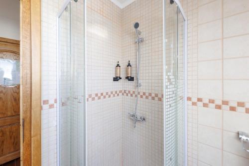 a bathroom with a shower with white tiles at Hanul Ancutei in Arămoaia
