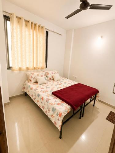 a bedroom with a bed with a red blanket on it at Elite Nest Stay in Nashik