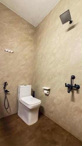 a bathroom with a white toilet in a room at Kadapu stay in Udiyāvara