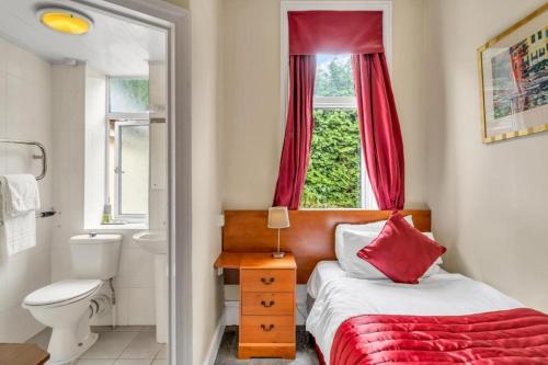 a bedroom with a bed and a toilet and a window at Seka Inn Hotel in Crowthorne