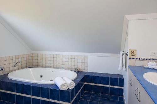 baño de azulejos azules con bañera y lavamanos en Villa 5 Whitesands en Dunsborough